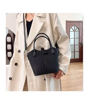 Detailed view of women's black woven shoulder handbag with top handles and stylish crossbody strap.