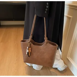 Detailed view of the brown vintage tote bag with double straps and stylish bead charm.