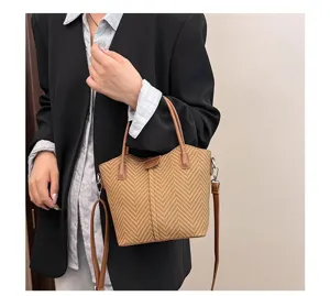 Detail shot of casual woven bucket handbag with brown leather trim and shoulder strap.