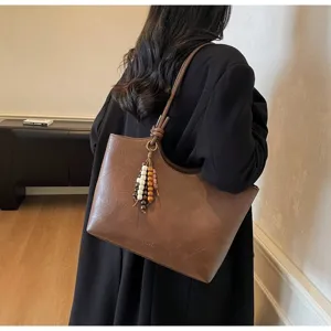 Classic brown PU leather tote bag for women, stylish vintage shoulder bag with tassel charm.