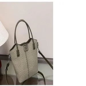 Detailed view of casual woven handbag detail, herringbone pattern with leather handle.