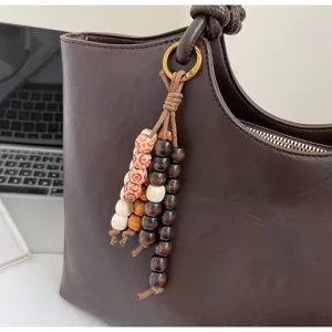 Dark brown leather tote bag featuring a chic wooden bead charm for daily commuting style.