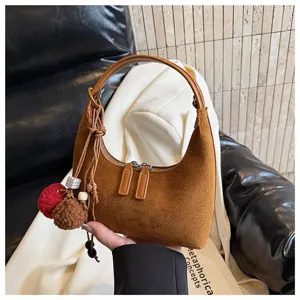Retro brown suede hobo bag for women, stylish dumpling handbag with chic tassels and pom-poms.