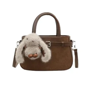 Chic brown suede handbag with cute plush rabbit pendant, elegant shoulder crossbody bag.