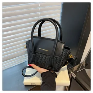 Detalle de bolso de mano tejido negro con diseño de cuero texturizado y elegante correa de hombro.