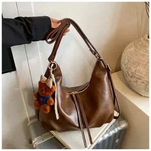 Detailed close-up of brown PU leather hobo shoulder bag with cute bear pendant charm.