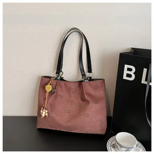 Braune Shopper Tasche aus Wildleder mit Blumen-Ausschnitt, schwarzen Trägern und Anhänger.