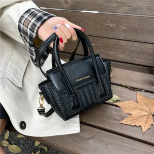 Vista detallada de un elegante bolso de mano negro tejido con asa y textura única.