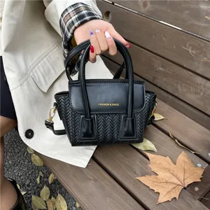 Vista detallada del bolso de mano tejido en negro con asas dobles y textura elegante.