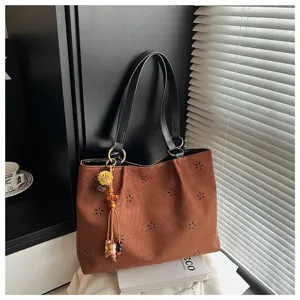 Modische braune Wildleder-Tasche für Damen, mit Blumen-Ausschnitt und elegantem Schulterriemen.