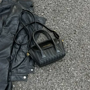 Bolso de hombro de cuero tejido negro con asa superior y diseño de solapa elegante.