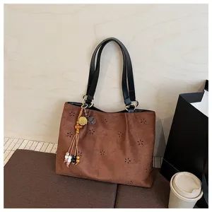 Braune Wildleder Shopper Tasche Detail mit Lochblumenmuster und stylischem Fransen Anhänger.