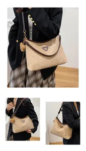 Detail view of stylish suede shoulder bag with brown trim, large hobo tote and cute bear charm.