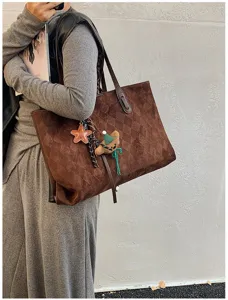 Detail view of the vintage brown suede quilted tote bag, showcasing texture and cute charms.