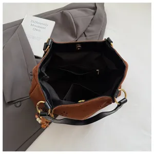 Braune Schultertasche aus Wildleder mit Blumenausschnitt, schwarzen Griffen und Innentaschen.
