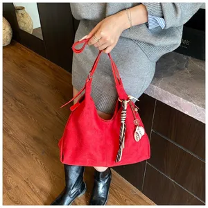 Detailed view of red suede hobo shoulder bag with tassel charm and large capacity for autumn.