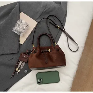 Detailed view of the brown suede crossbody bag with vintage drawstring and metallic buckle.