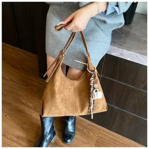 Detail shot of a brown suede vintage hobo shoulder bag with charm for women commuting.