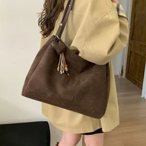 Detailed view of the retro brown suede shoulder tote bag with heart charm and chic tassel accent.
