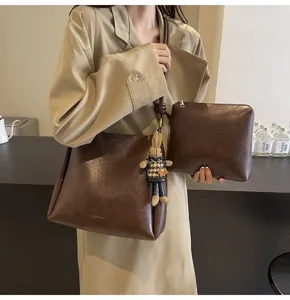 Stylish brown PU leather bucket bag set with shoulder strap, matching pouch and cute rabbit charm.