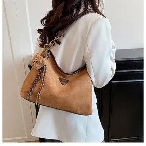 Brown suede shoulder bag for women, stylish underarm hobo bag with cute bear pendant.
