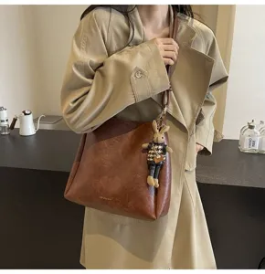 Chic brown shoulder bucket bag detail view featuring premium leather texture and cute bunny charm.