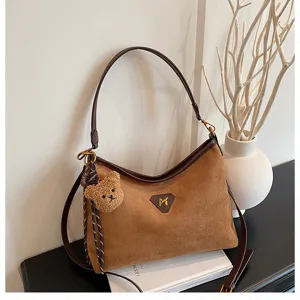 Suede shoulder bag detail, brown hobo bag with cute bear charm and durable leather strap.