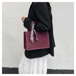 Burgundy suede tote bag with stylish scarf handle and embroidered letter front design for women.