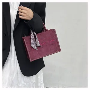 Burgundy suede tote bag with stylish patterned twilly scarf and embroidered letter design.