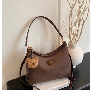 Dark brown suede shoulder bag detail, soft fabric texture with cute plush bear pendant.