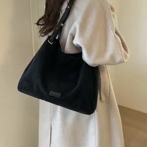 Detailed view of the stylish black suede shoulder bag worn by model, commuting hobo style.