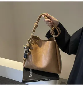 Chic khaki shoulder bag with knotted handle and cute rabbit pendant for women daily use.