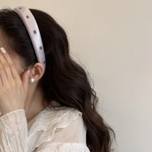 Dettaglio in primo piano dell'elegante cerchietto imbottito a pois, accessorio per capelli.