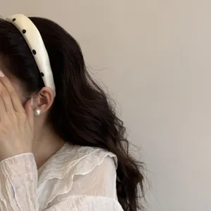Dettaglio del chic cerchietto in satin a pois, che mostra la morbida consistenza in spugna.