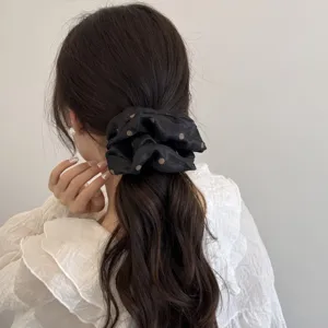 Detalle de coletero negro elegante con lunares, accesorio de cabello suave y estiloso para coleta.