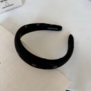 Vista dettagliata del cerchietto in raso a pois, accessorio per capelli chic per uso quotidiano.