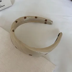 Cerchietto in raso beige con pois marroni, primo piano dettagliato di elegante accessorio per capelli.