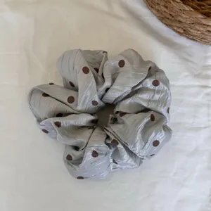 Vista detallada de un elegante coletero gris para el pelo con topos marrones.