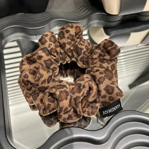 Primo piano dettagliato di scrunchie leopardato vintage, con tessuto morbido e finitura artigianale.