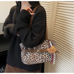Leopard print shoulder bag detail showing brown straps, metal buckles and cute plush bear pendant.