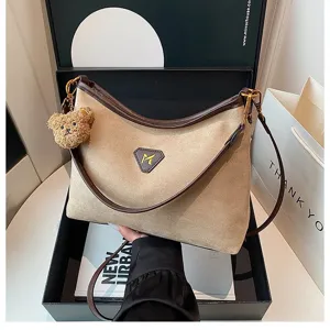 Detailed shot of trendy suede shoulder bag with cute bear pendant and spacious design.