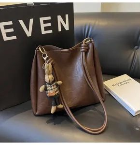Brown large capacity shoulder bag detail view, stylish commuter bucket bag with cute pendant.