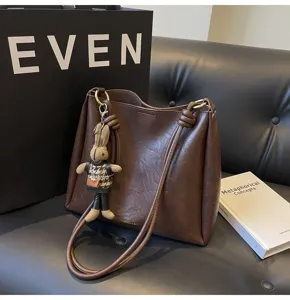 Stylish brown PU leather shoulder bucket bag with cute knit rabbit charm for women autumn.