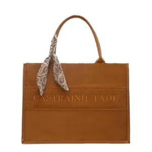 Brown suede tote bag with stylish scarf handle and embossed letter design for women daily use.