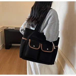 Detail view of the black corduroy tote bag showcasing multiple front pockets and brown trim.