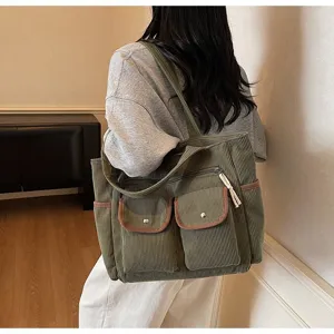 Green corduroy shoulder tote bag with multiple front pockets and brown trim detail in use.