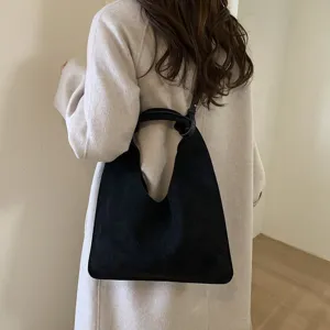 Detailed view of a black suede shoulder bag worn on model, showing retro lazy style and capacity.