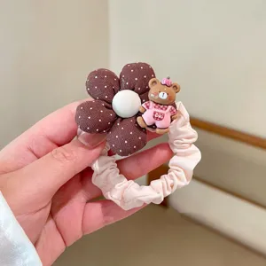 Primo piano dettagliato del grazioso elastico per capelli a pois marroni con tenero orsetto.