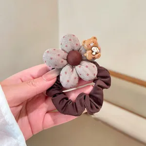 Primo piano dettagliato dell'elastico per capelli con fiore a pois marrone e orsetto.