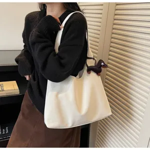 Minimalistische witte schoudertas detailweergave, grote hobo tas met leuke hondenhangdecoratie.
